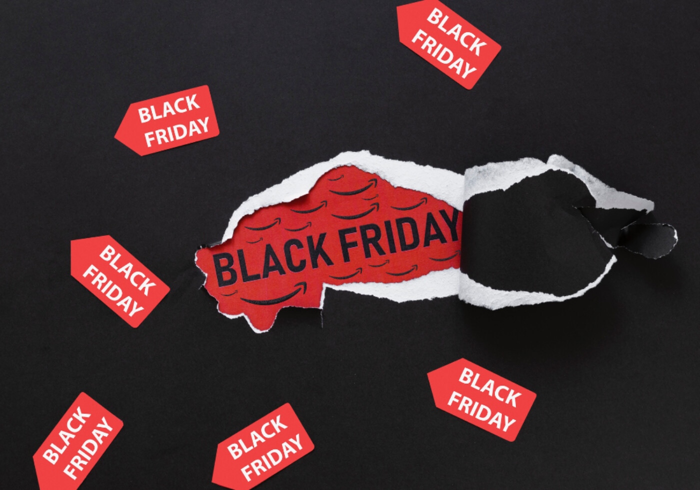 Torn black paper revealing Black Friday text with tags.