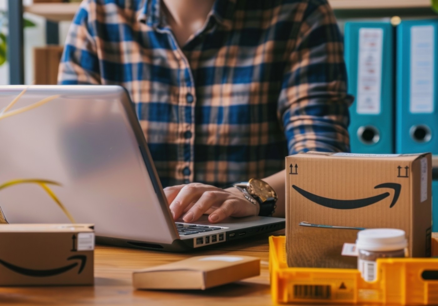 Person using a laptop with Amazon packages on the desk