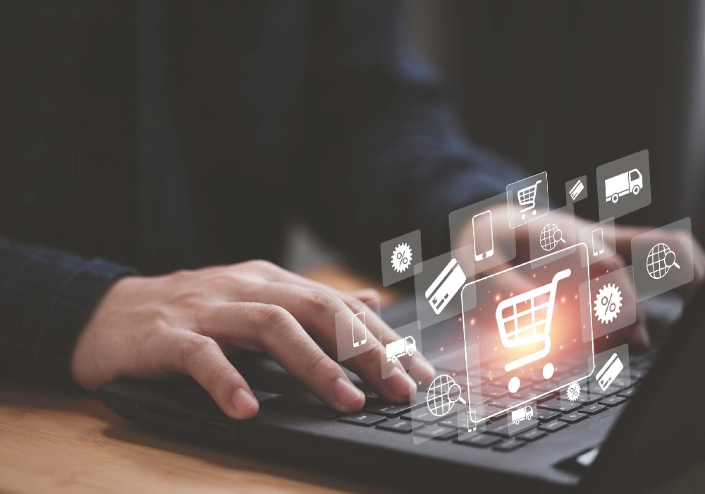 Close-up of hands typing on a laptop keyboard with floating e-commerce icons