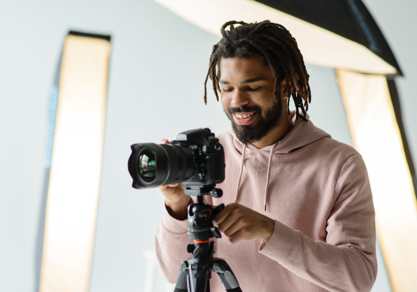 Photographer adjusting camera on tripod in a studio setting.