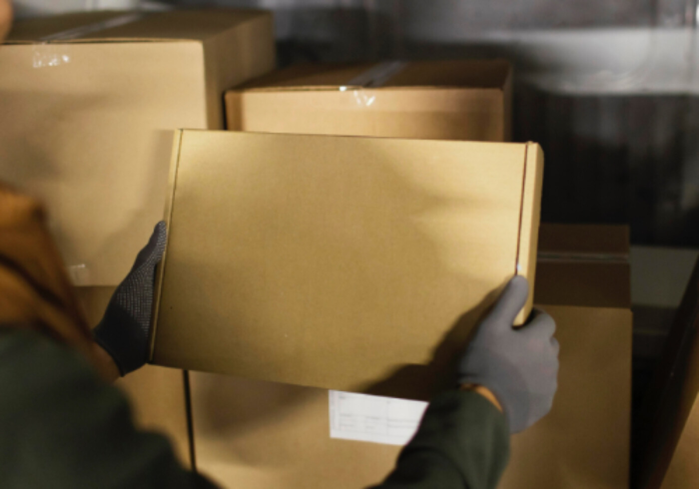 Person handling a cardboard box in a storage area.