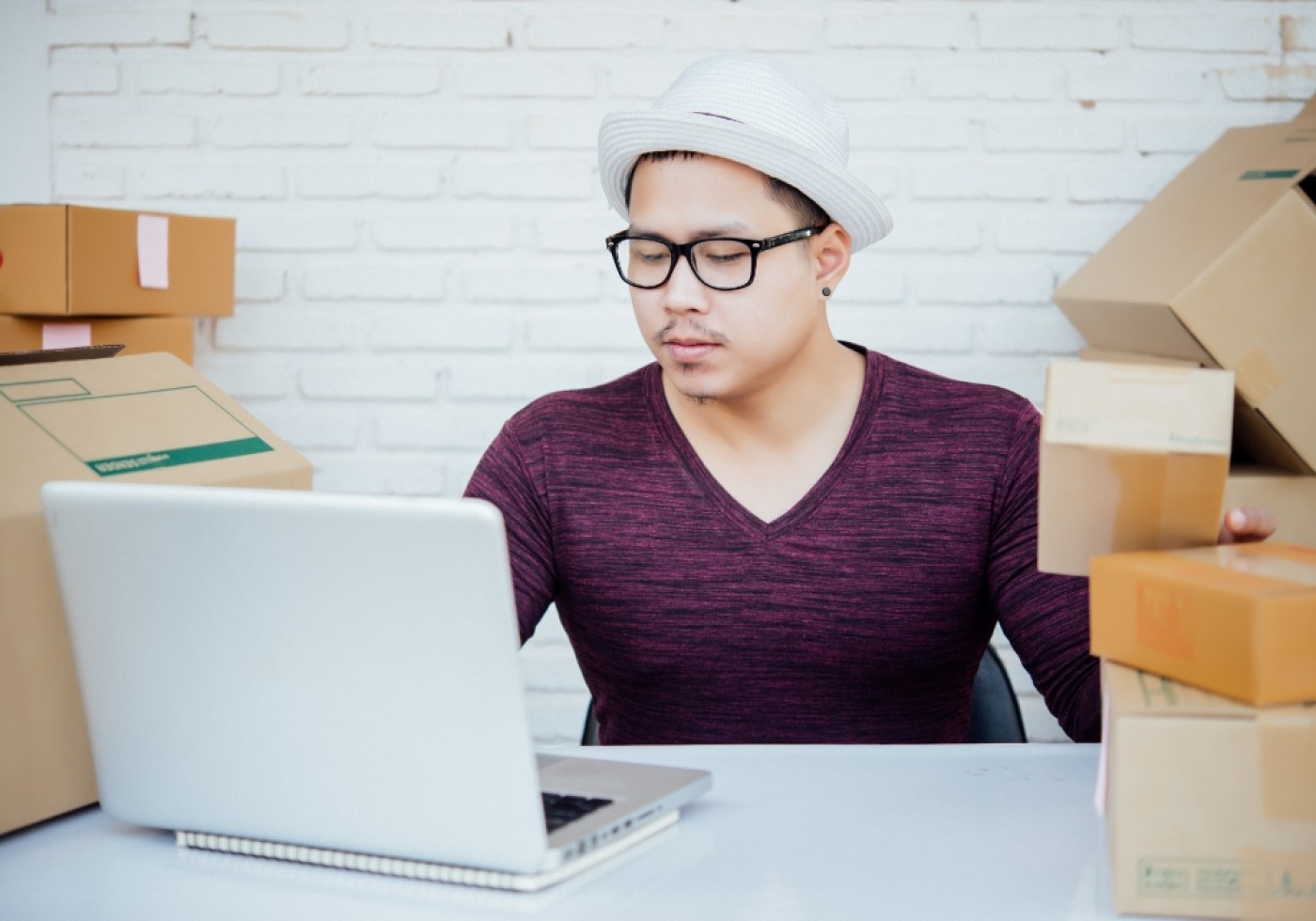 Man managing online orders with laptop and packages.