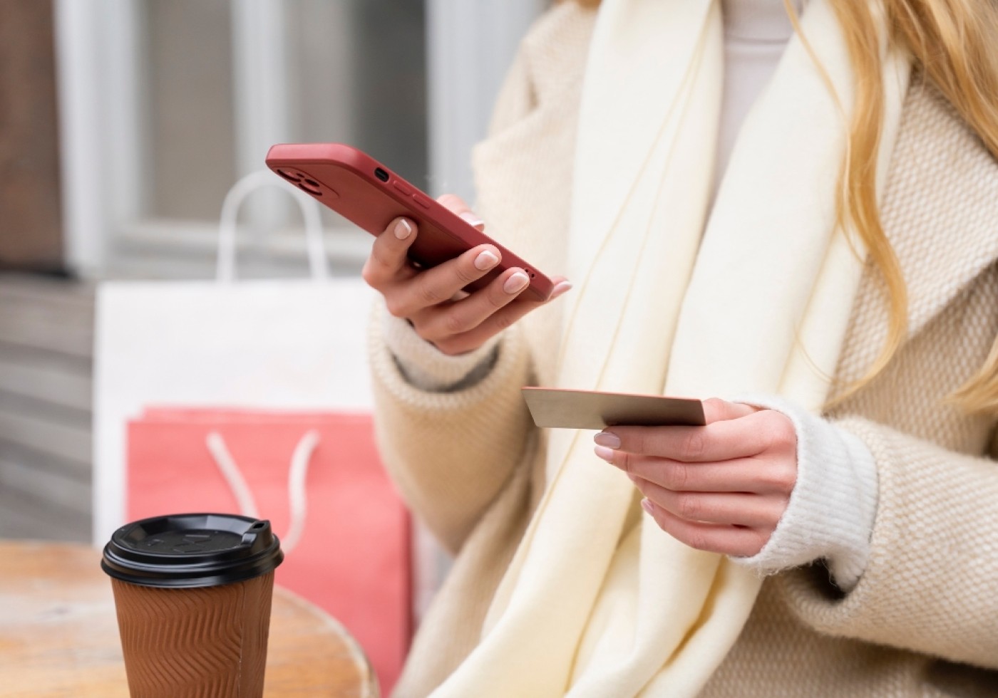 A woman holding a smartphone in one hand and a credit card in the other