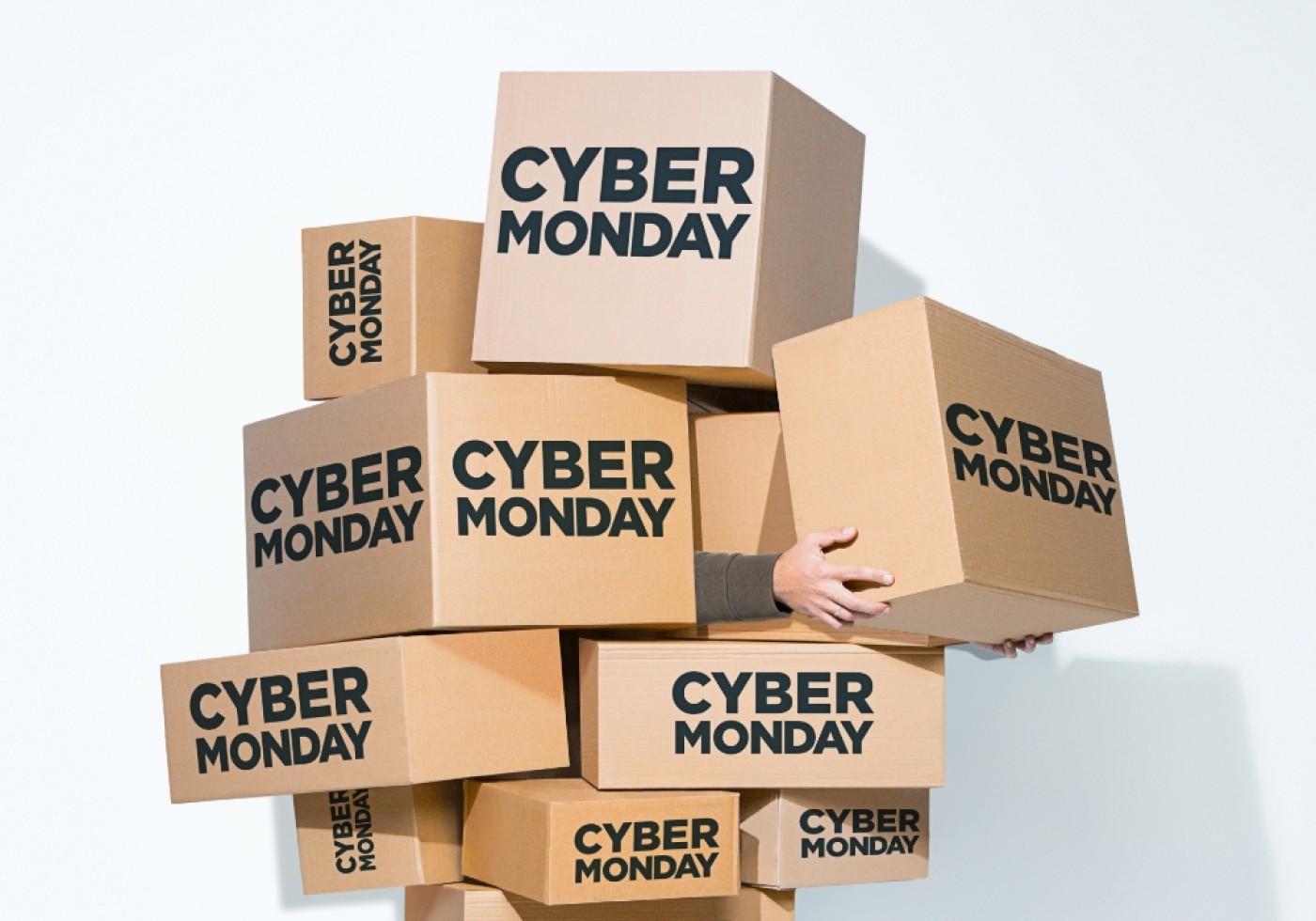 Person holding a stack of cardboard boxes labeled 'Cyber Monday.'