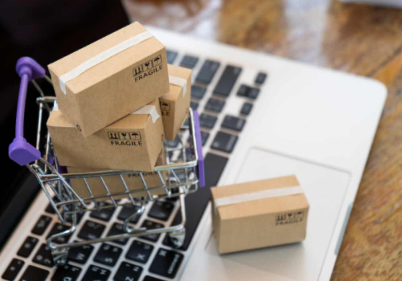 Mini shopping cart with small packages on a laptop keyboard.