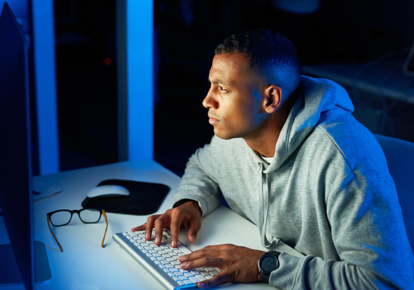 Man working late at a computer with focused expression.