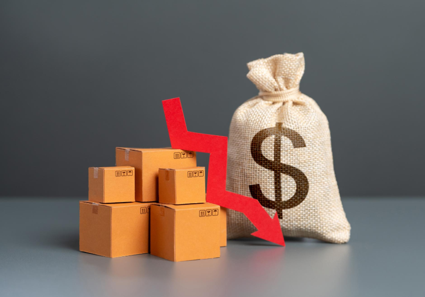 Stacked boxes with a dollar bag and downward arrow symbolizing sales decline.