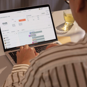 Man with glasses using the Amzigo platform dashboard on a MacBook Pro laptop