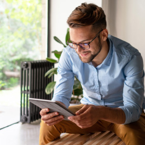 Smiling man sitting and reading from a tablet