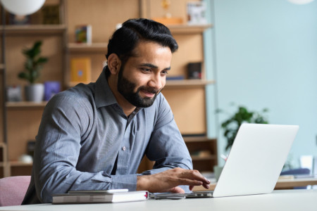 Smiling man using a laptop at a desk